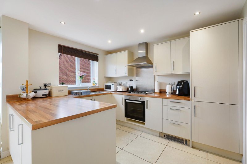 Modern kitchen with cream cabinetry, wooden countertops, island and stainless steel appliances
