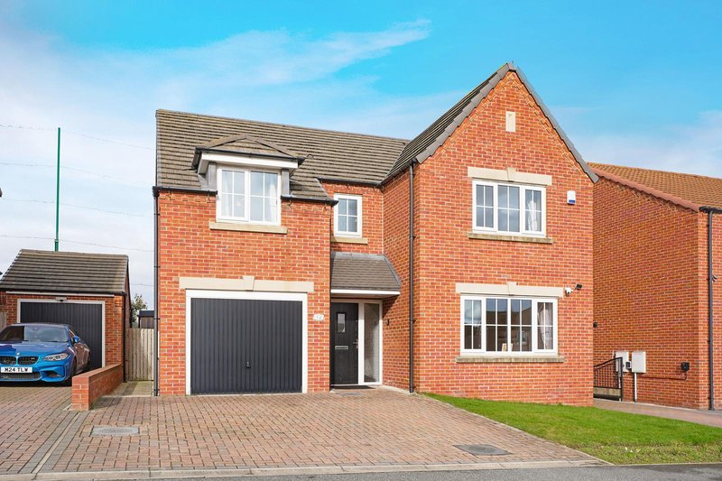 Red brick detached house with driveway, garage, and manicured front garden
