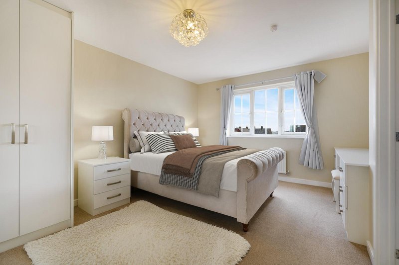 Bright bedroom with upholstered bed, bedside lamps, wardrobe, and large window with curtains