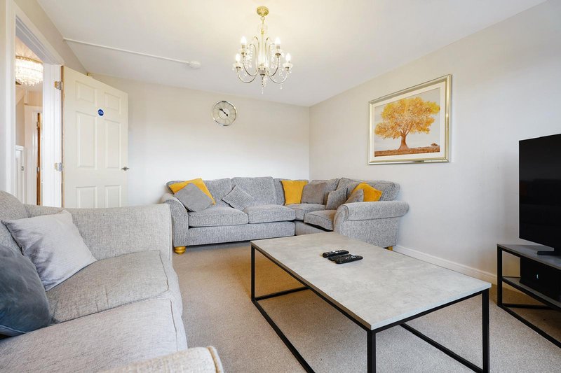 Bright living room with gray sectional sofa, marble coffee table, TV, and framed artwork
