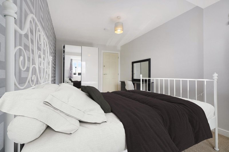 Modern bedroom with white metal bed frame, white pillows, black duvet, and geometric wall art