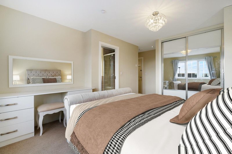 Modern bedroom with double bed, white dresser, mirrored wardrobe and ceiling light