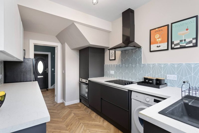 Modern kitchen with black cabinets, white countertops, geometric backsplash and framed wall art