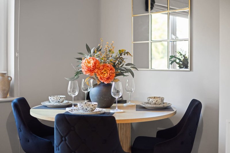 Dining room with round table, blue velvet chairs, and floral centerpiece