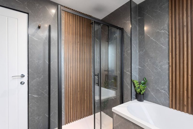 Modern bathroom with marble walls, glass shower enclosure, white vanity and wooden paneling