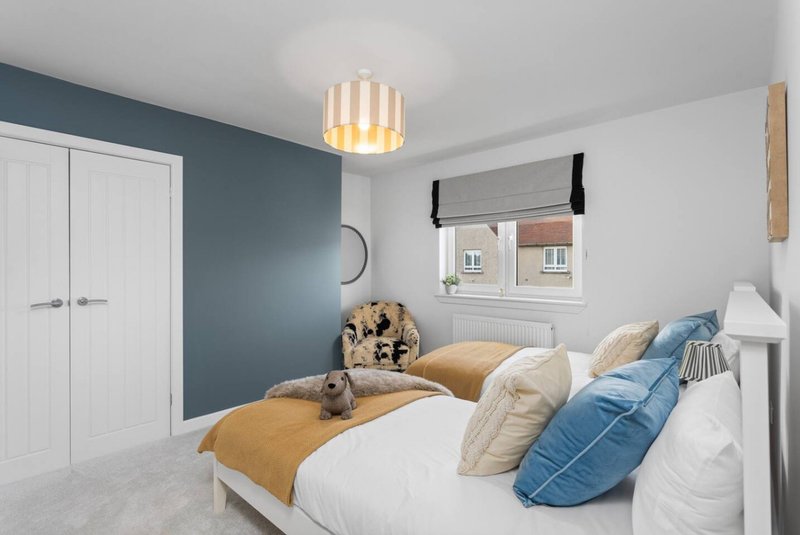 Modern bedroom with double bed, blue accent wall, white wardrobe and pendant light