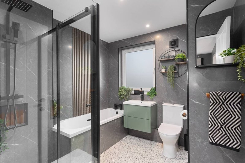 Modern bathroom with grey tile walls, shower enclosure, green vanity unit and toilet