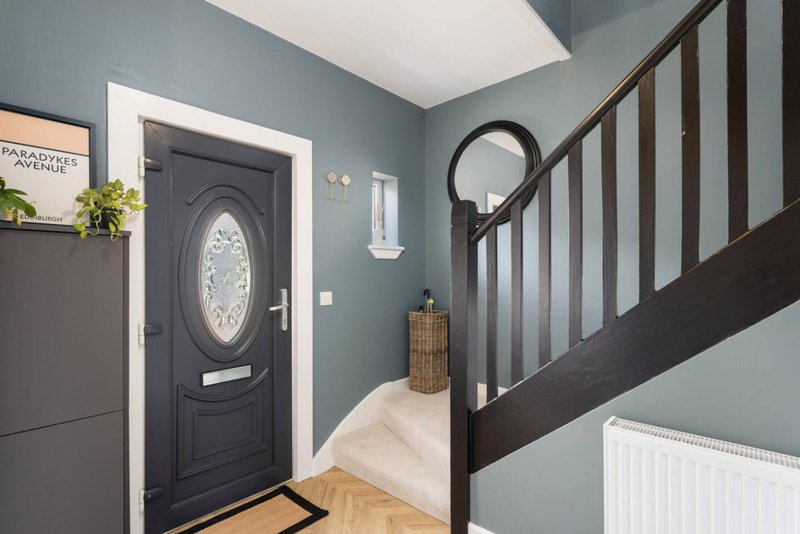 Hallway with black front door, staircase, teal walls and wooden flooring