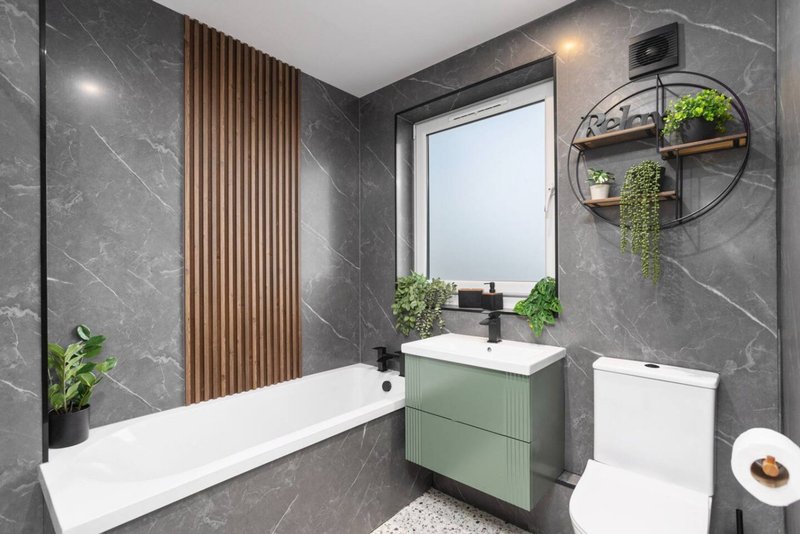 Modern bathroom with bathtub, green vanity, toilet, circular mirror shelf and window