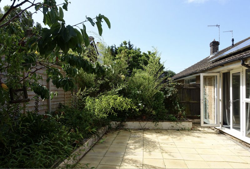 Patio garden area with paving, raised beds, climbing plants, and building extension