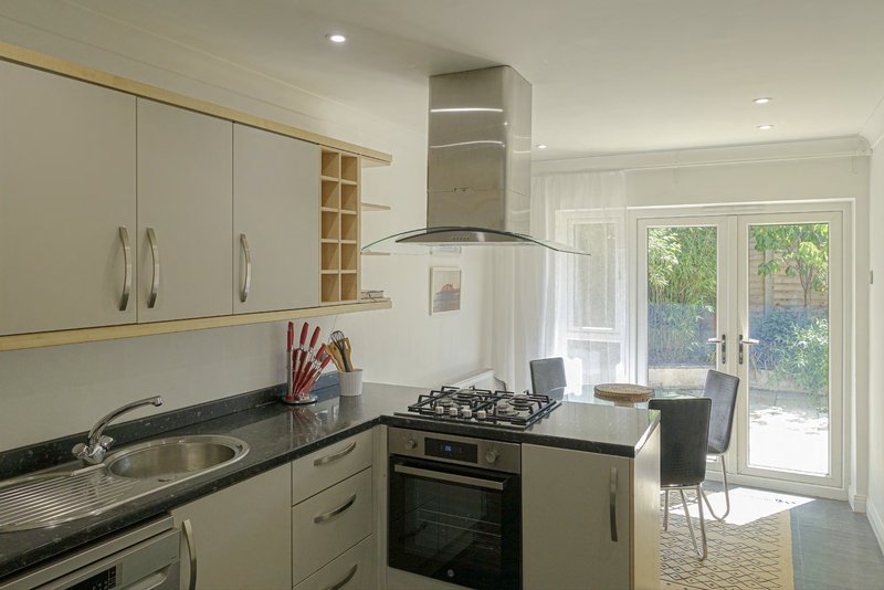 Modern kitchen with cream cabinets, black countertops, gas range, and glass doors to garden