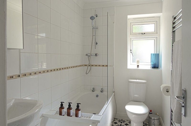 Modern bathroom with shower enclosure, toilet, window and heated towel rail
