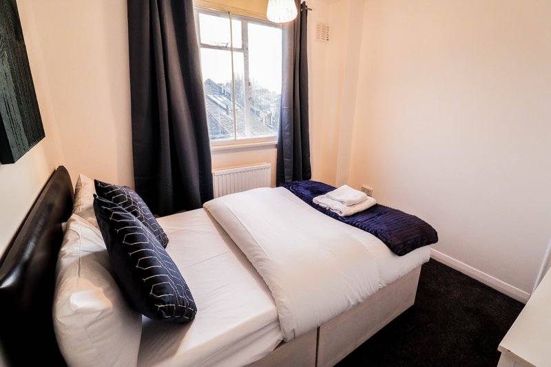 Bedroom with two single beds, white bedding, dark curtains and mountain view window