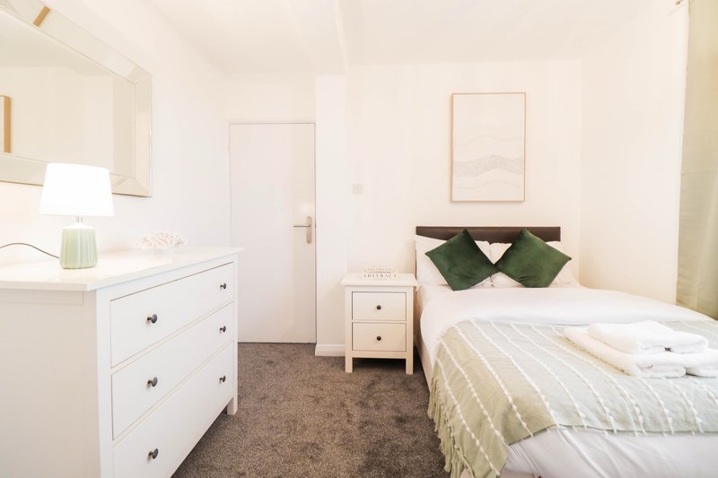 Bright bedroom with single bed, white dresser, bedside table and cream walls