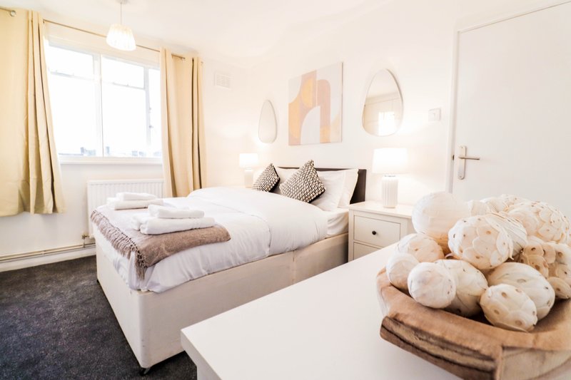 Modern bedroom with double bed, pendant lighting, artwork, and window with curtains