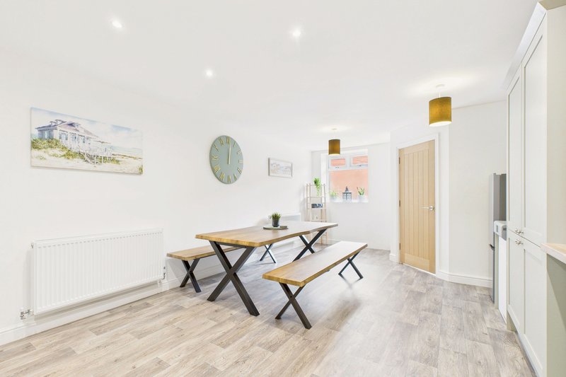 Bright open-plan dining area with wooden table, benches, and light wood flooring