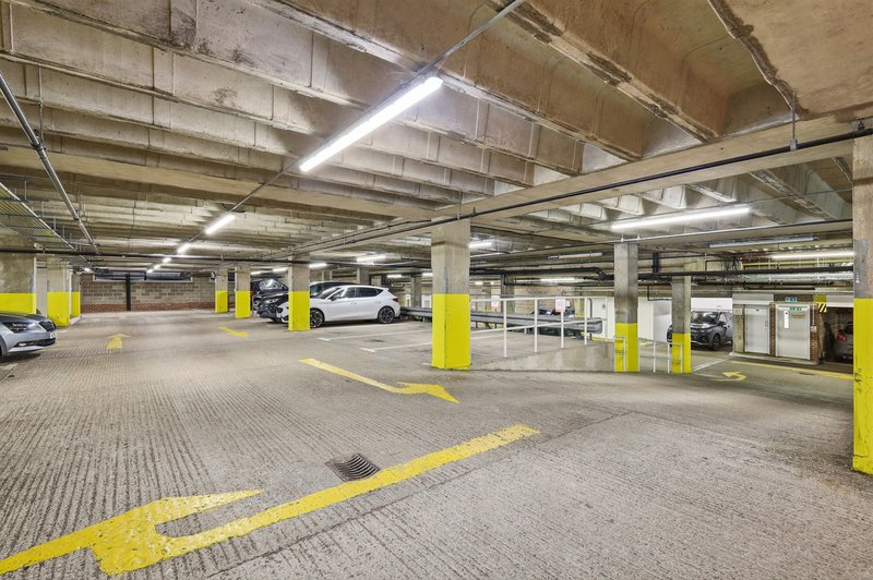 Underground parking garage with yellow pillars, lined spaces, and parked vehicles