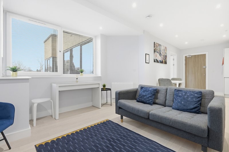 Modern living room with grey sofa, desk by window, blue rug and armchair