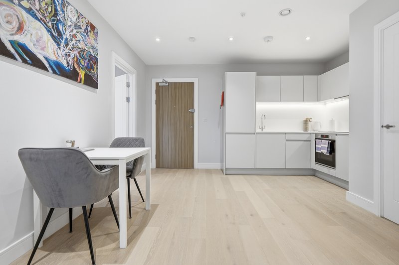 Modern open-plan kitchen and dining area with white cabinetry, light wood flooring, and gray dining chairs
