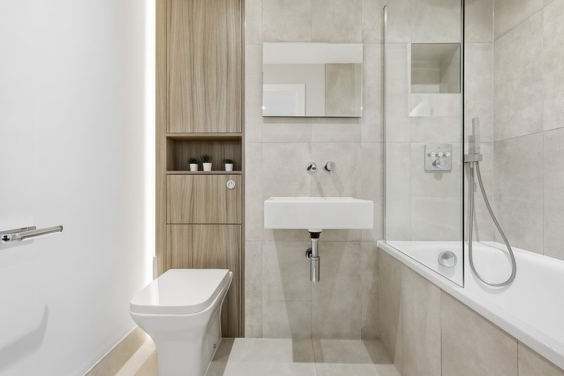 Modern bathroom with toilet, sink, mirror, shower enclosure and wooden storage unit