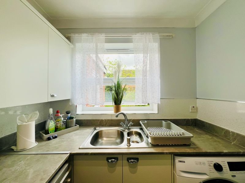Kitchen with sink, window, green countertop and white wall cabinets