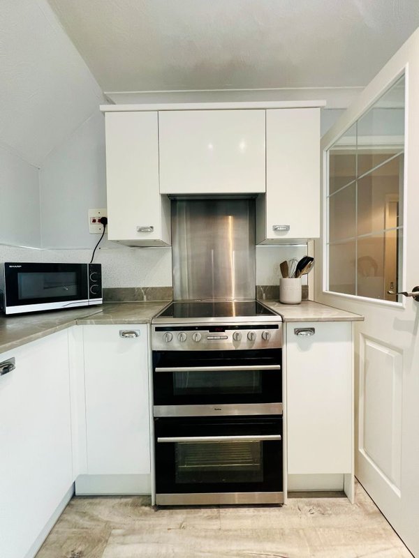 Modern kitchen with white cabinets, stainless steel double oven, and microwave