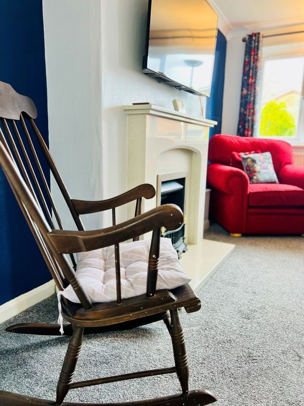 Living room with wooden chair, fireplace, red sofa, and blue accent wall