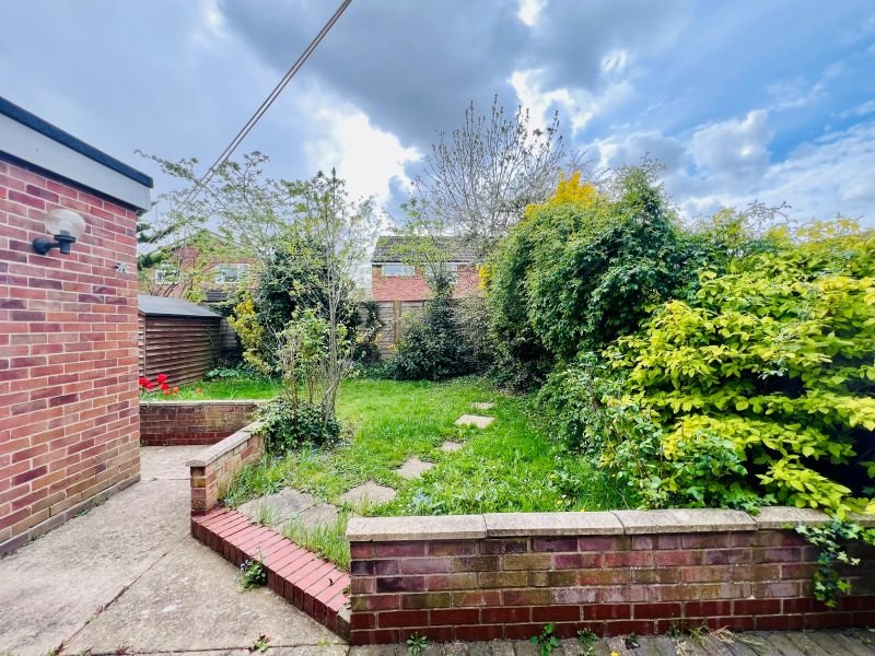 Brick-built garden with raised beds, mature vegetation, paving and utility structures