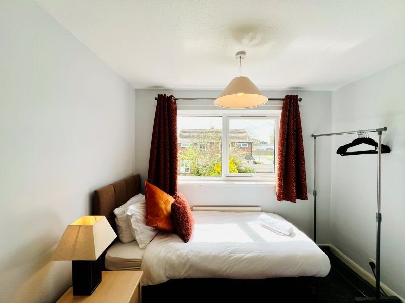 Modern bedroom with double bed, pendant light, window view, and bedside lamp
