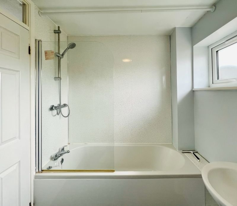 Clean bathroom with bathtub, glass shower screen and window