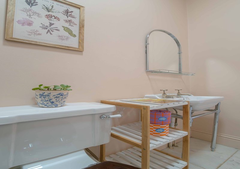 Bathroom with freestanding tub, wooden vanity, sink, mirror and potted plant