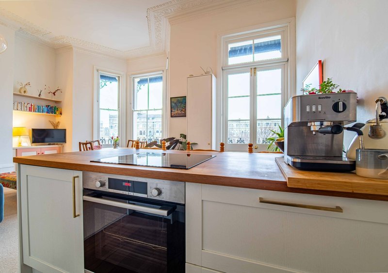 Modern kitchen with white cabinetry, wooden countertop, built-in oven and large windows