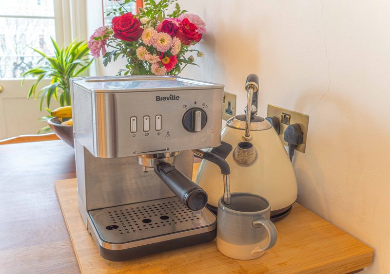 Kitchen counter with Breville espresso machine, accessories, flowers and potted plants by window