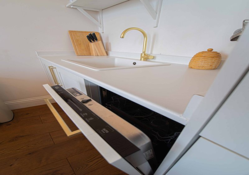 Modern kitchen with white counter, brass faucet, wooden cutting boards and open drawer