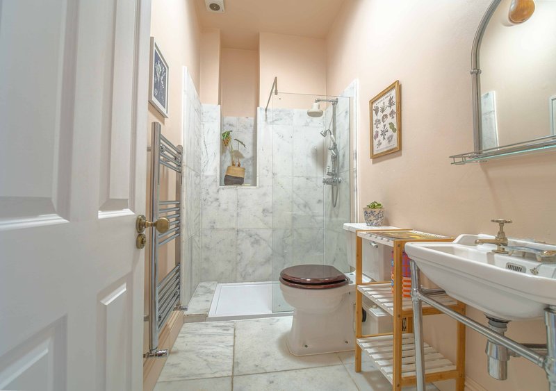 Bathroom with walk-in shower, toilet, sink, towel rail and peach-colored walls
