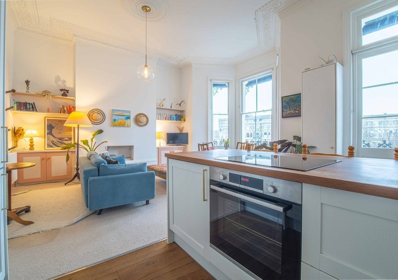 Open-plan kitchen and living area with blue armchair, wooden countertop, and city views