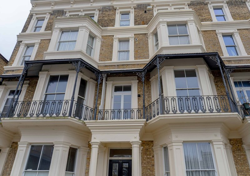 Classical Victorian townhouse facade with cream columns, brick detailing and wrought-iron balconies