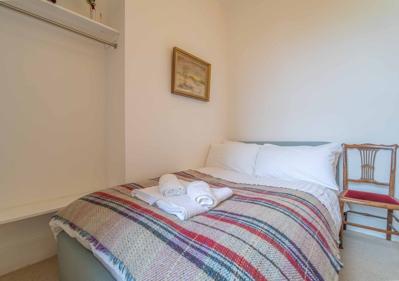 Bedroom with double bed, striped bedding, white pillows and wooden chair