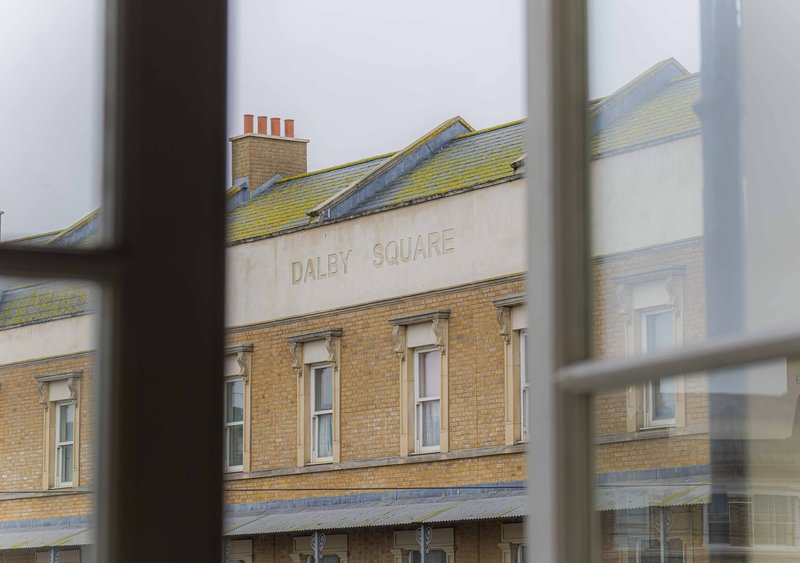 View of Victorian brick building with Dalby Square signage from window perspective