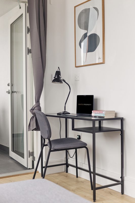 Modern home office corner with black desk, chair, desk lamp and framed wall art