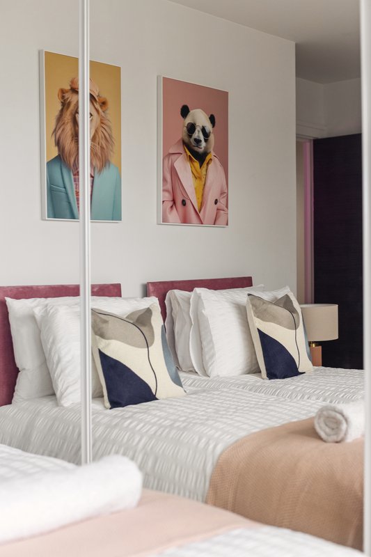 Modern bedroom with mirrored wardrobe, bed with decorative pillows, and animal artwork on walls