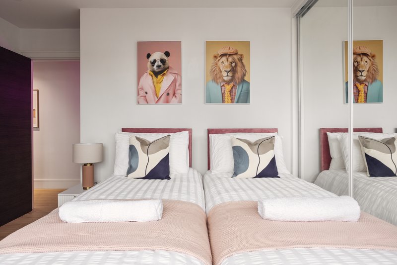 Modern bedroom with two double beds, decorative animal artwork, mirrored wardrobe and bedside lamp
