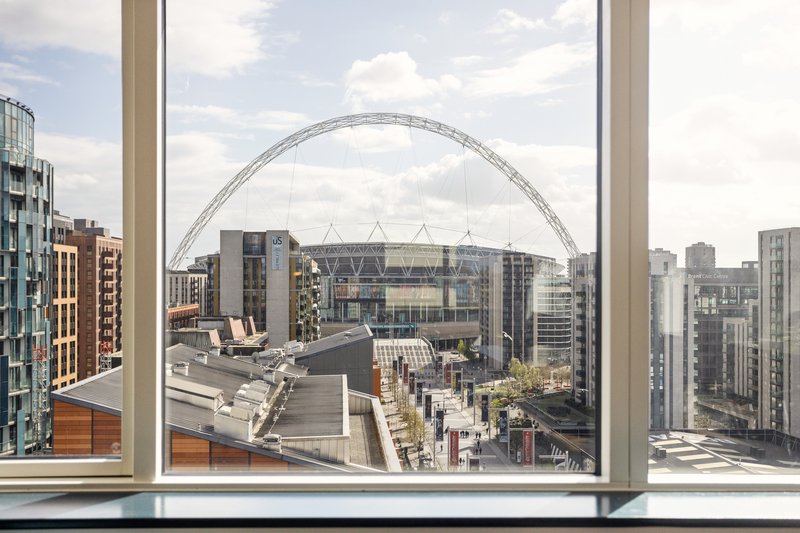 City skyline view through large window with Wembley Stadium arch visible in distance