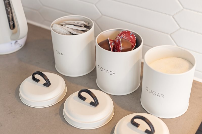 Kitchen counter with white ceramic storage canisters labeled tea, coffee and sugar