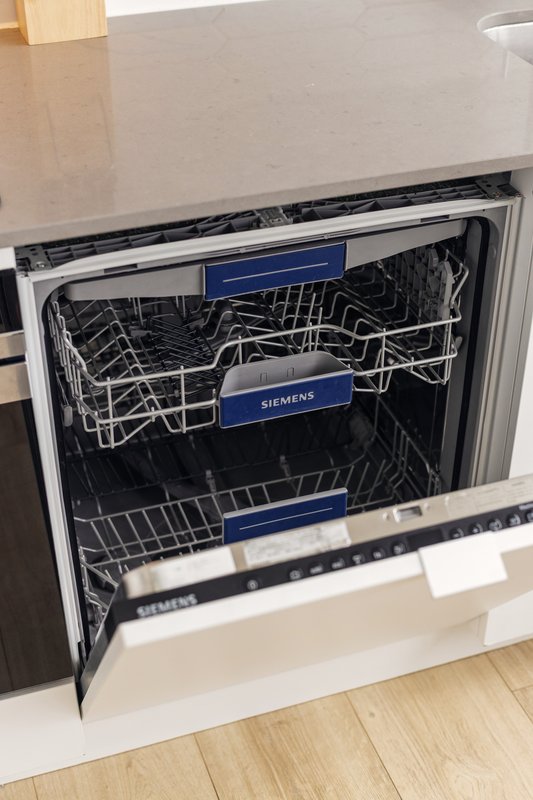 Built-in dishwasher with open door showing interior racks and Siemens branding