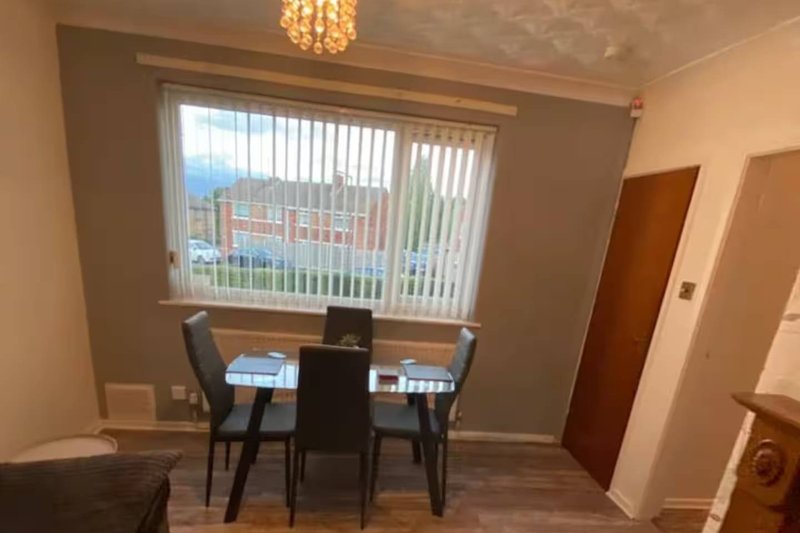 Dining area with black table, chairs, and window overlooking urban street view