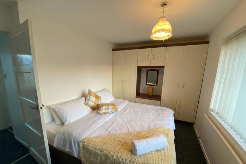 Bedroom with double bed, white bedding, wardrobe, pendant light and window