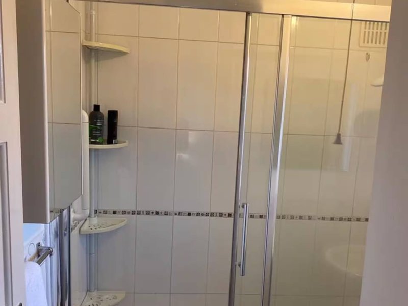 Modern shower enclosure with glass doors, white tile walls, and chrome fixtures