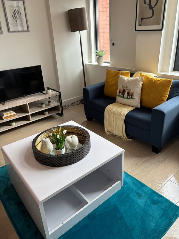 Modern living room with blue sofa, white coffee table, TV stand and floor lamp