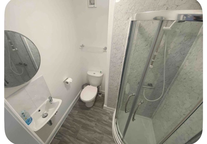 Bathroom with toilet, sink, mirror, and glass shower enclosure with vinyl flooring